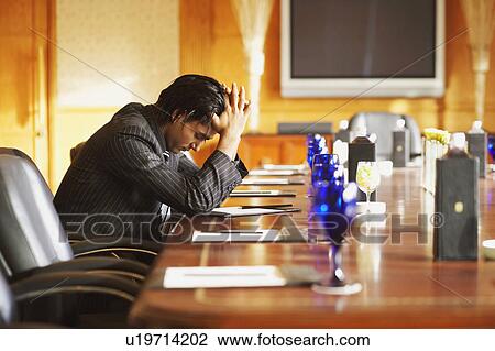 Stock Image - Side profile of a businessman relaxing in a conference room. Fotosearch