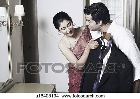 Young woman holding a suit in front of a young man View Large Photo Image Picture - Young woman holding a suit in front of a young man. Fotosearch