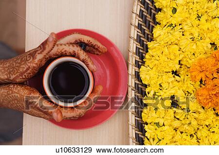 Stock Photo - Close-up of a woman's henna tattooed hands holding a cup of tea. Fotosearch
