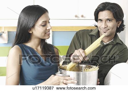 Stock Photo - Close-up of a young couple cooking raw spaghetti. Fotosearch