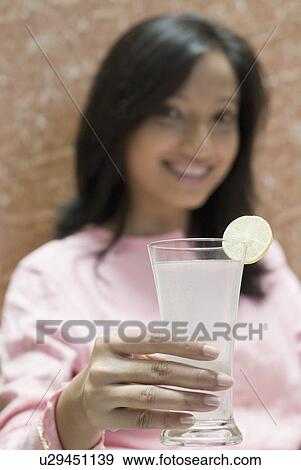 Close-up of a young woman holding a glass of lemonade View Large Photo Image Stock Photo - Close-up of a young woman holding a glass of lemonade. Fotosearch
