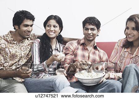 Close-up of two young couples sitting together on a couch eating popcorn View Large Photo Image Stock Image - Close-up of two young couples sitting together on a couch eating popcorn. Fotosearch