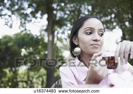 Stock Image - Low angle view of a teenage girl holding a cup of tea. Fotosearch