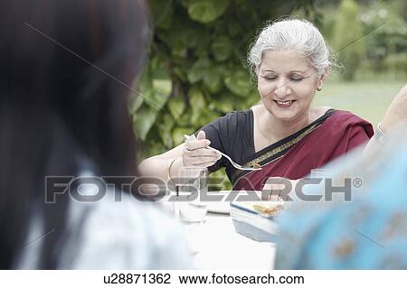 Stock Image - Mature woman sitting at a dining table. Fotosearch