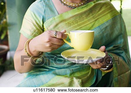 Mid section view of a young woman holding a cup of tea View Large Photo Image Stock Image - Mid section view of a young woman holding a cup of tea. Fotosearch