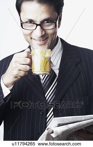 Portrait of a businessman holding a tea cup and a newspaper View Large Photo Image Stock Photography - Portrait of a businessman holding a tea cup and a newspaper. Fotosearch