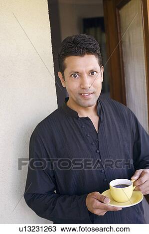 Stock Image - Portrait of a mid adult man holding a cup of tea. Fotosearch