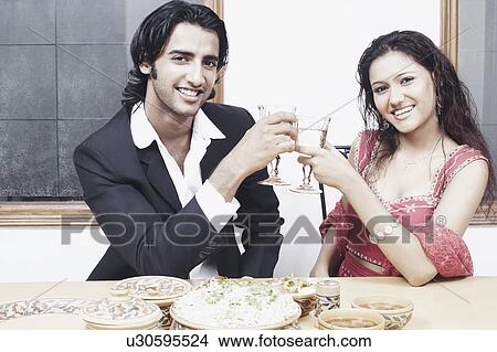 Portrait of a young couple toasting with wineglass at the dining table View Large Photo Image Picture - Portrait of a young couple toasting with wineglass at the dining table. Fotosearch