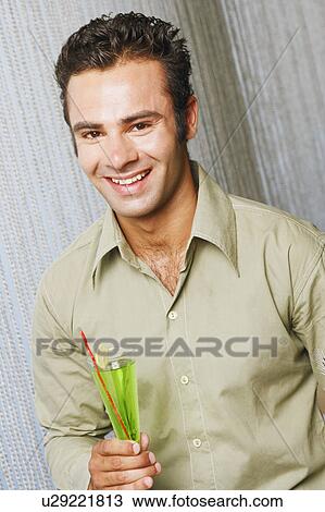 Portrait of a young man holding a glass and smiling View Large Photo Image Stock Image - Portrait of a young man holding a glass and smiling. Fotosearch