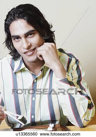 Portrait of a young man holding sushi with chopsticks and smiling View Large Photo Image Stock Image - Portrait of a young man holding sushi with chopsticks and smiling. Fotosearch