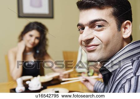 Portrait of a young man sitting at the dining table with his friends View Large Photo Image Stock Photography - Portrait of a young man sitting at the dining table with his friends. Fotosearch