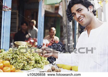 Portrait of a young man standing at a fruit stand View Large Photo Image Stock Photo - Portrait of a young man standing at a fruit stand. Fotosearch