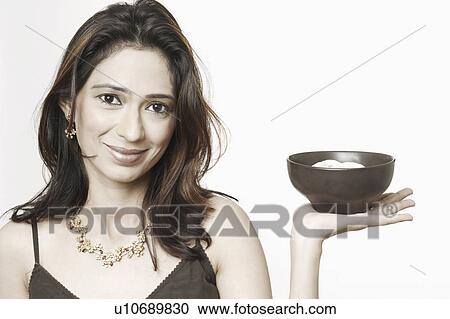 Stock Image - Portrait of a young woman holding a bowl of food. Fotosearch