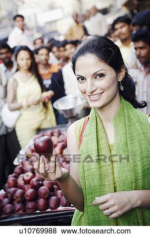 Stock Photo - Portrait of a young woman holding an apple. Fotosearch