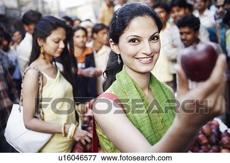 Stock Photo - Portrait of a young woman holding an apple. Fotosearch