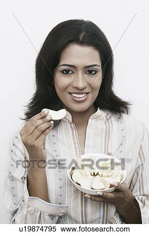 Portrait of a young woman picking a slice of apple from a bowl View Large Photo Image Stock Photography - Portrait of a young woman picking a slice of apple from a bowl. Fotosearch