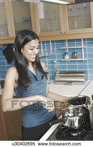 Young woman cooking in the kitchen View Large Photo Image Stock Photography - Young woman cooking in the kitchen. Fotosearch