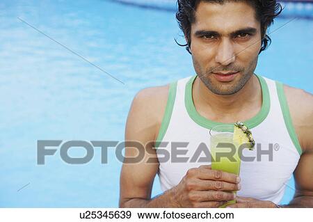 Portrait of a young man smiling and holding a glass of juice View Large Photo Image Stock Photo - Portrait of a young man smiling and holding a glass of juice. Fotosearch