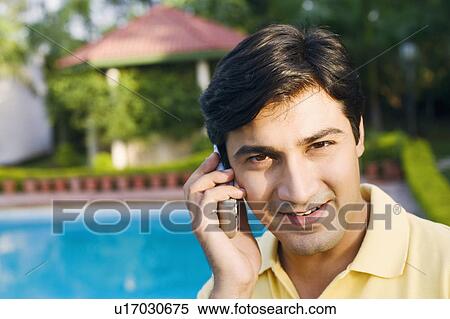 Portrait of a young man talking on a mobile phone and smiling View Large Photo Image Stock Photography - Portrait of a young man talking on a mobile phone and smiling. Fotosearch