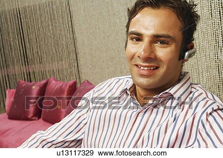 Stock Photo - Portrait of a young man wearing a hands free device. Fotosearch