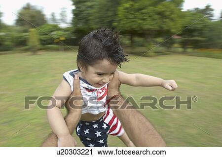 Stock Image - Close-up of a man's hand swinging a boy in air. Fotosearch