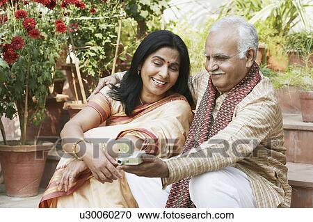 Close-up of a mature couple looking at a digital camera View Large Photo Image Stock Image - Close-up of a mature couple looking at a digital camera. Fotosearch