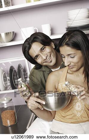 Stock Photo - Close-up of a young couple holding herbs in two small jars. Fotosearch
