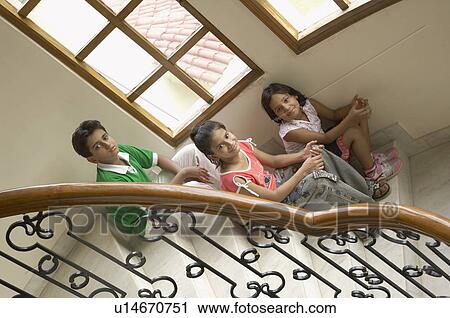 High angle view of a boy and two girls sitting on a staircase and smiling View Large Photo Image Stock Image - High angle view of a boy and two girls sitting on a staircase and smiling. Fotosearch