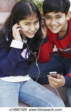Portrait of a boy and his sister listening to an MP3 player View Large Photo Image Stock Photo - Portrait of a boy and his sister listening to an MP3 player. Fotosearch