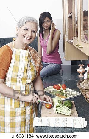 Picture - Portrait of a mature woman cutting vegetables in the kitchen. Fotosearch