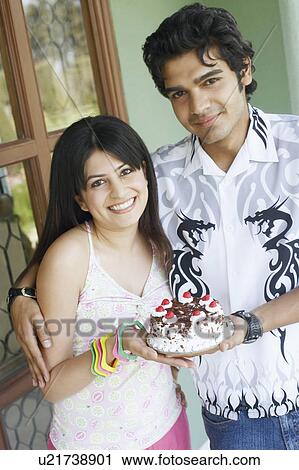 Portrait of a young couple smiling and holding a birthday cake View Large Photo Image Stock Image - Portrait of a young couple smiling and holding a birthday cake. Fotosearch