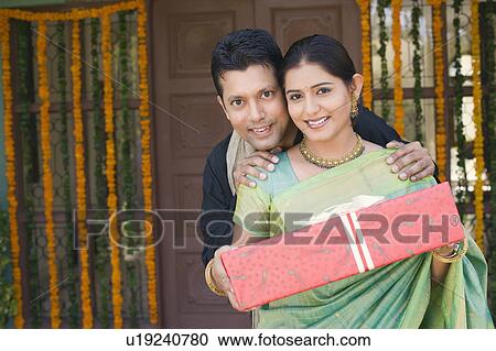 Portrait of a young woman and a mid adult man holding a gift View Large Photo Image Stock Image - Portrait of a young woman and a mid adult man holding a gift. Fotosearch