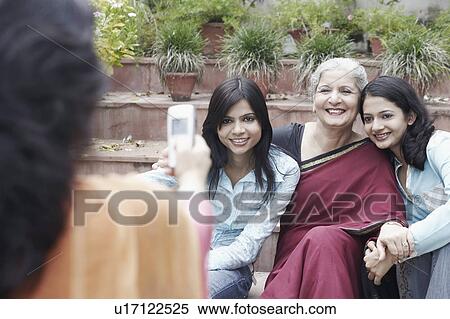 Stock Photography - Rear view of a woman holding a mobile in front of three women. Fotosearch