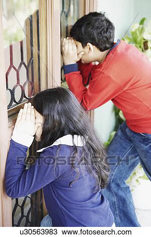 Side profile of a boy and his sister peeping through a window View Large Photo Image Stock Image - Side profile of a boy and his sister peeping through a window. Fotosearch