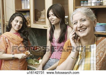 Stock Image - Three women standing in the kitchen. Fotosearch