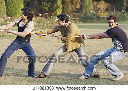 Stock Photo - Three young men playing tug-of-war. Fotosearch