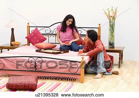 Stock Photo - Young couple holding cups of tea in the bedroom. Fotosearch