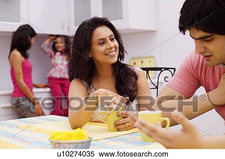 Young man and a mid adult woman sitting at a dining table View Large Photo Image Stock Photography - Young man and a mid adult woman sitting at a dining table. Fotosearch