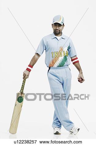 Stock Photo - Portrait of a young man holding a cricket bat and a cricket ball. Fotosearch