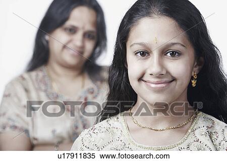 Portrait of a girl smiling with her mother standing behind her View Large Photo Image Stock Photography - Portrait of a girl smiling with her mother standing behind her. Fotosearch