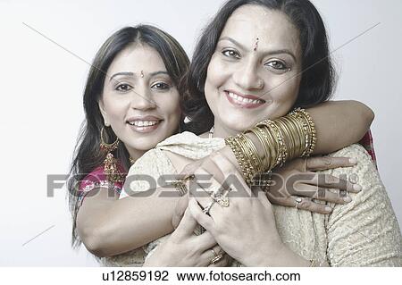 Stock Image - Portrait of a mid adult woman hugging a mature woman. Fotosearch