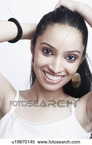 Stock Photography - Portrait of a teenage girl standing with her hands in her hair. Fotosearch