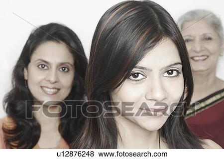 Stock Photo - Portrait of a young woman smiling with two women standing behind her. Fotosearch