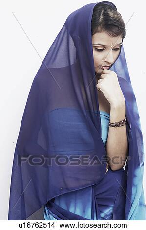 Picture - Young woman with her hand on her chin looking down. Fotosearch