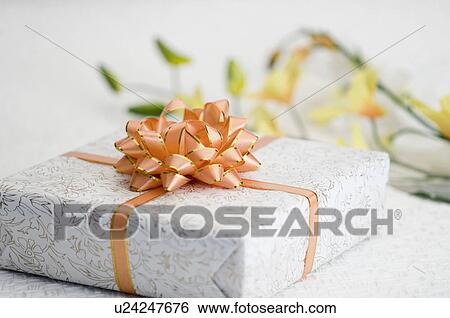 Stock Photograph - Close-up of a gift with flowers in the background. Fotosearch