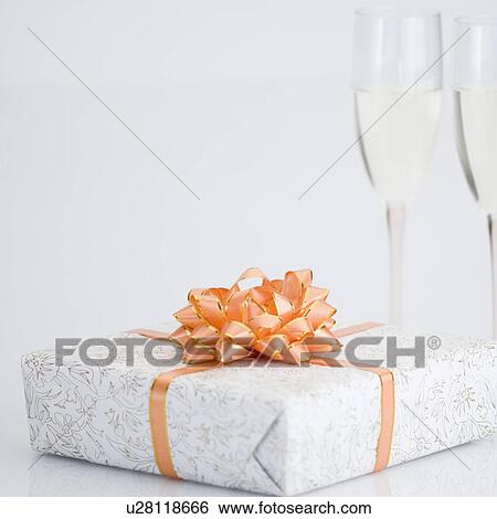 Stock Photograph - Close-up of a gift with two champagne flutes. Fotosearch