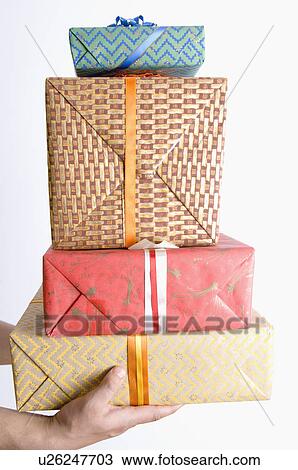 Stock Image - Close-up of a person's hand holding a stack of gifts. Fotosearch