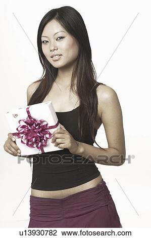 Stock Image - Portrait of a young woman holding a gift. Fotosearch