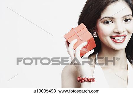 Stock Image - Portrait of a young woman holding a gift. Fotosearch
