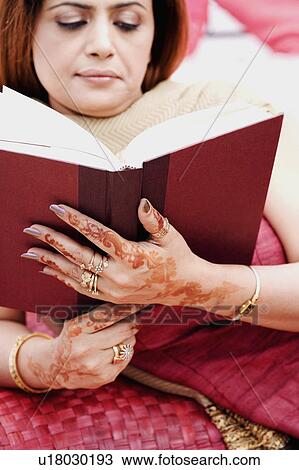 Close-up of a mid adult woman lying on the bed and reading a book View Large Photo Image Stock Image - Close-up of a mid adult woman lying on the bed and reading a book. Fotosearch